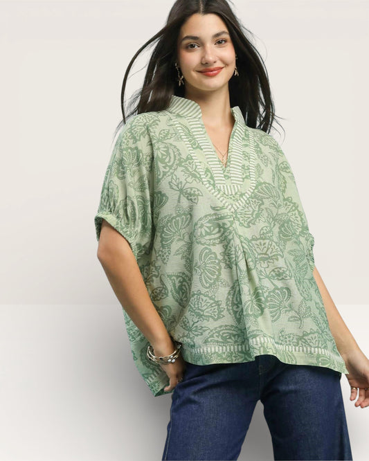 Woman wearing a green patterned top against a white background