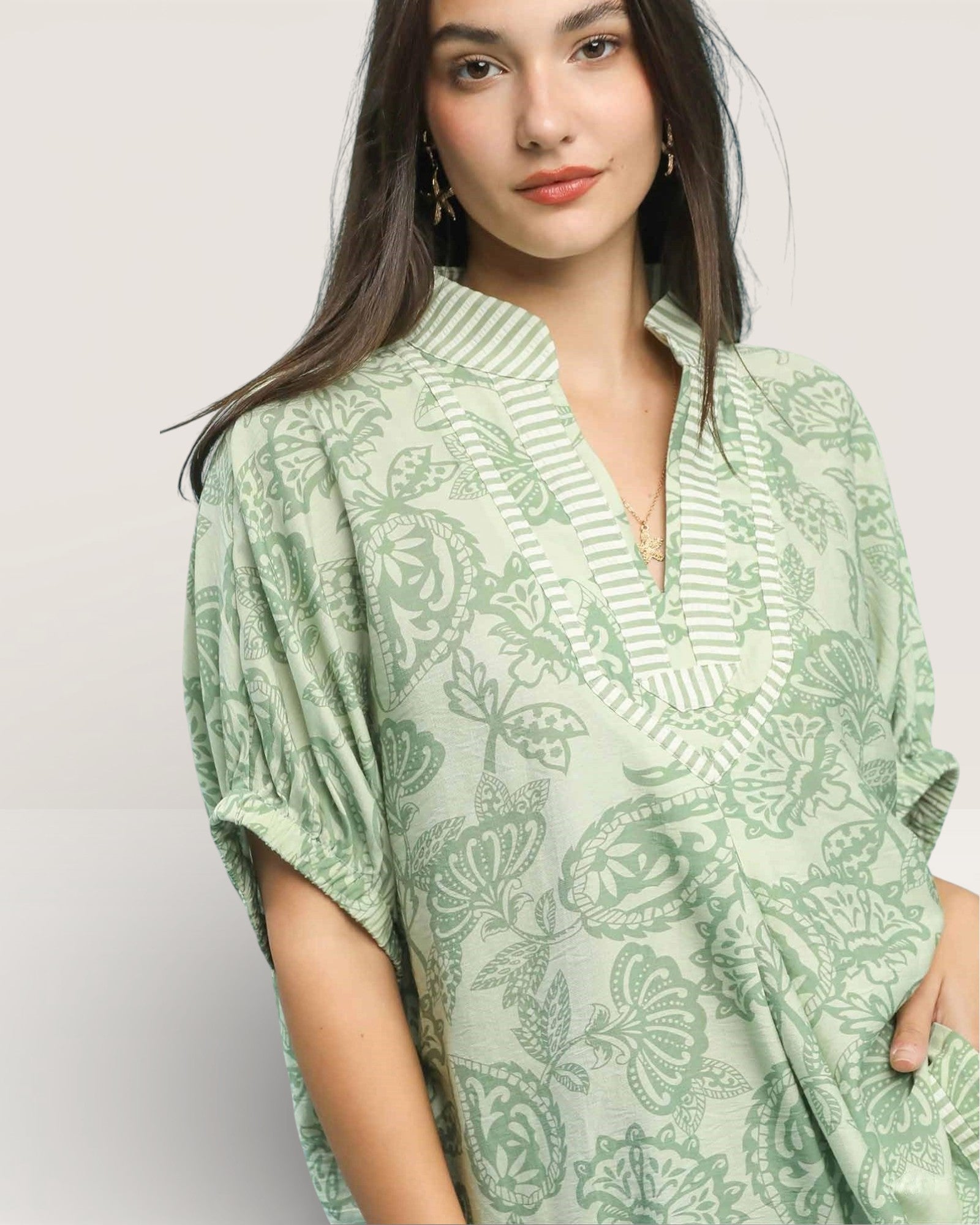 Woman wearing a green patterned top against a plain background
