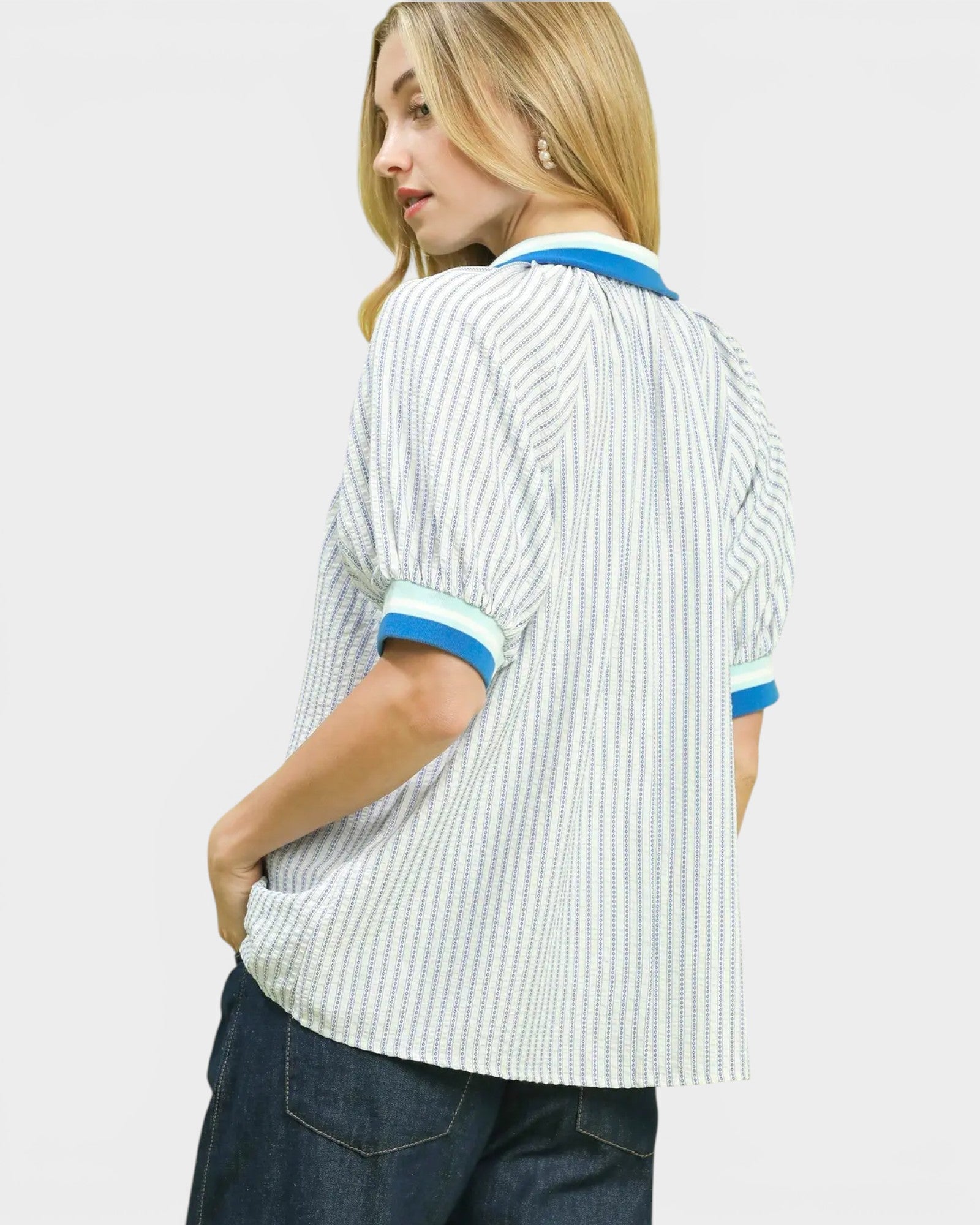 Person wearing a white and blue striped shirt on a plain background