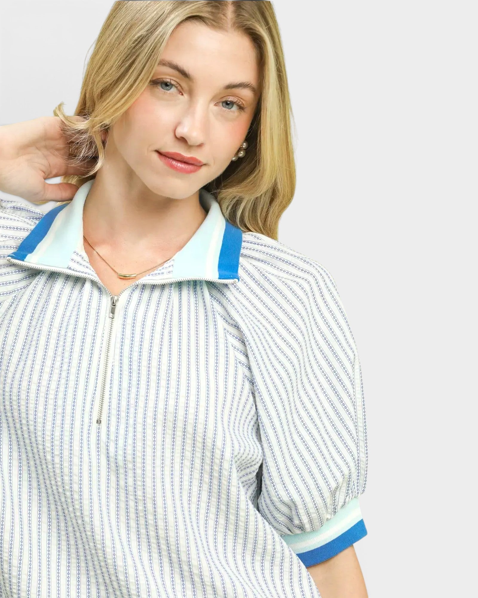 Woman wearing a striped shirt with blue trim on a plain background