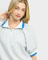 Woman wearing a striped shirt with blue trim on a plain background