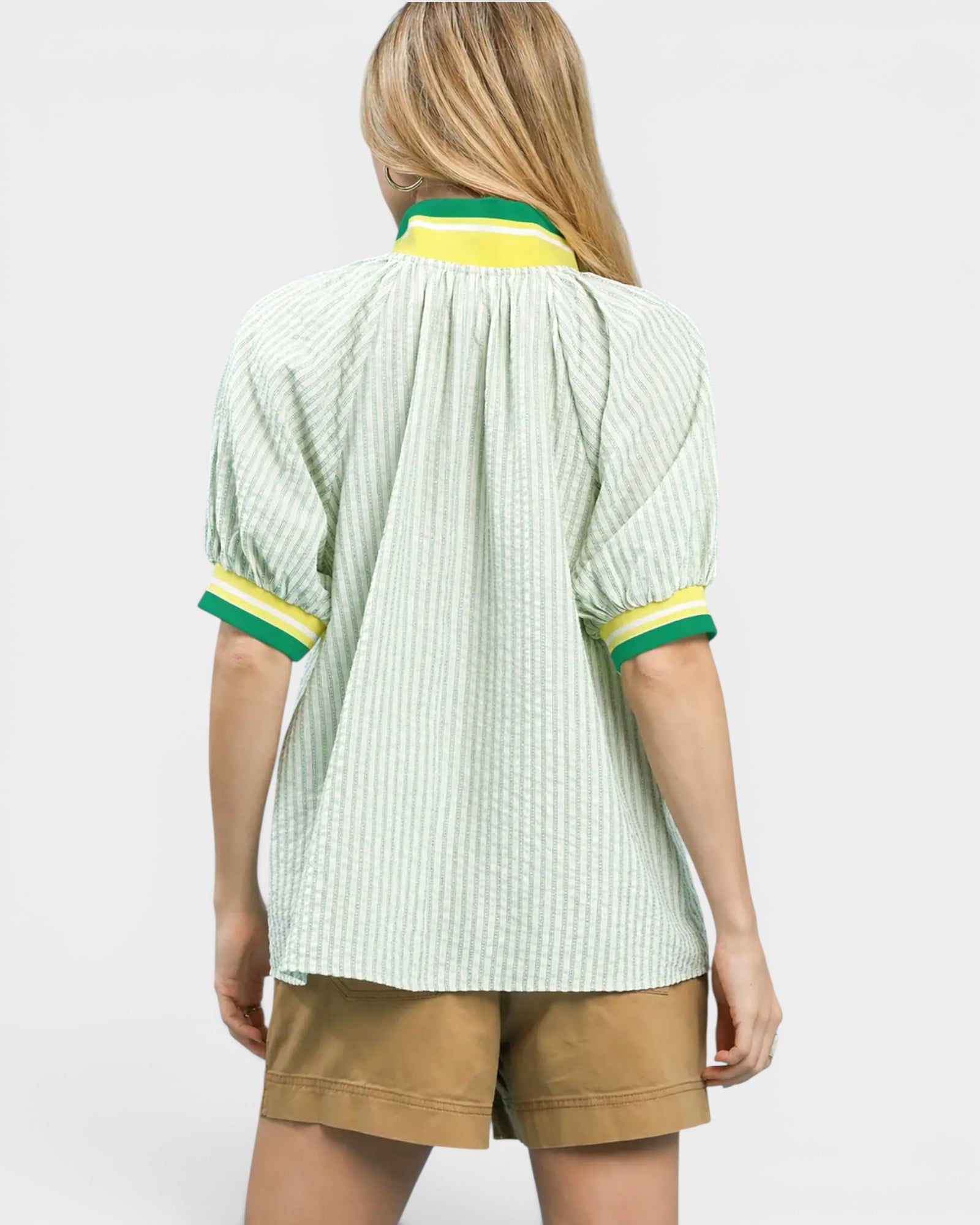 Person wearing a light green striped shirt with yellow accents on a white background