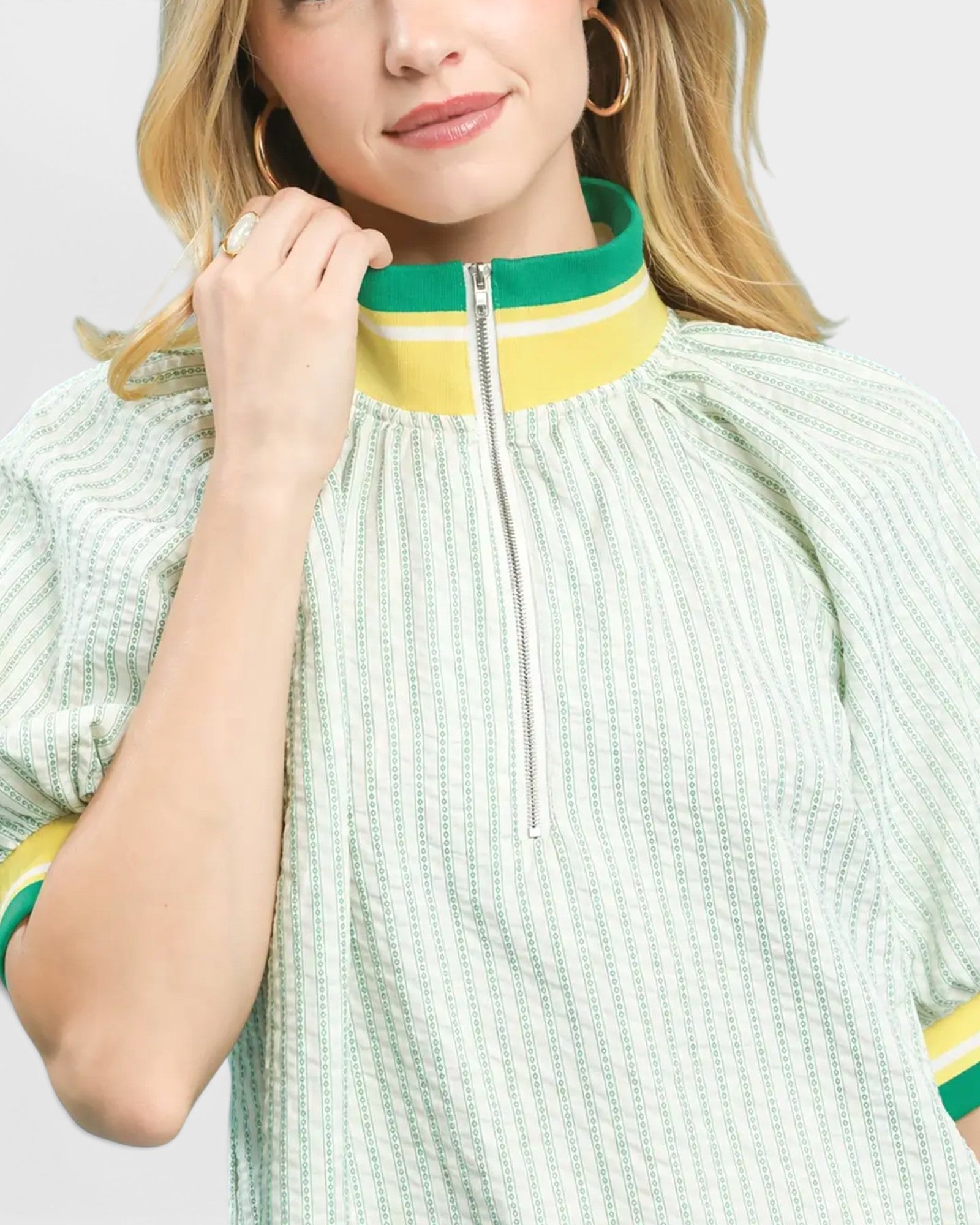 Person wearing a green and yellow striped dress with a plain background