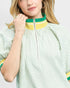 Person wearing a green and yellow striped dress with a plain background