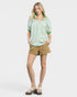 Woman wearing a green and white striped shirt with beige shorts on a white background