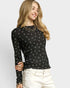 Woman wearing a black long-sleeve top with white patterns on a light gray background