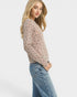 Woman wearing a sheer floral blouse and jeans on a white background
