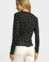 Woman wearing a black long-sleeve top with white patterns on a plain background