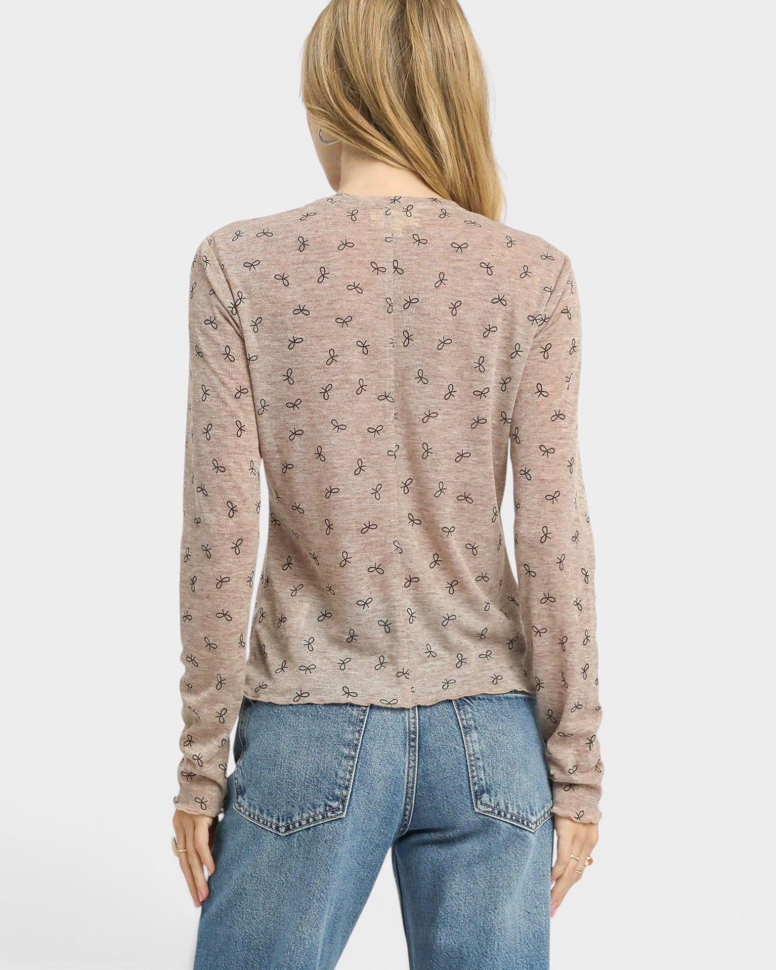 Person wearing a patterned long-sleeve shirt and blue jeans on a white background