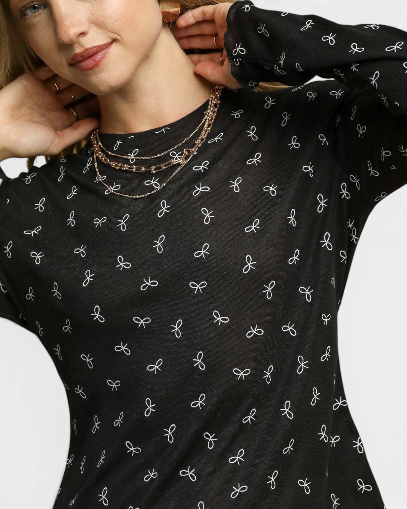 Person wearing a black long-sleeve shirt with white bow pattern
