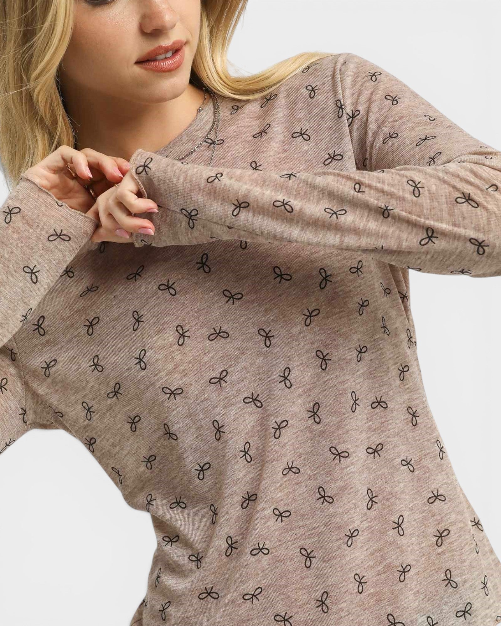 Woman wearing a brown long-sleeve shirt with black bow pattern on a white background