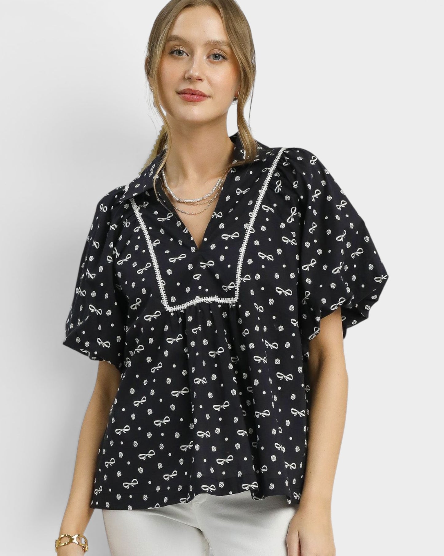 Woman wearing a black blouse with white patterns on a plain background