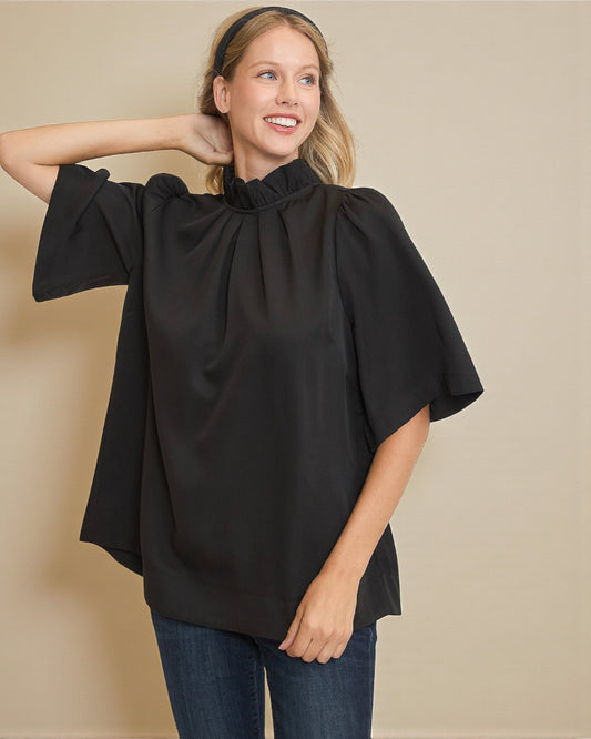 Woman wearing a black poncho over a plain background