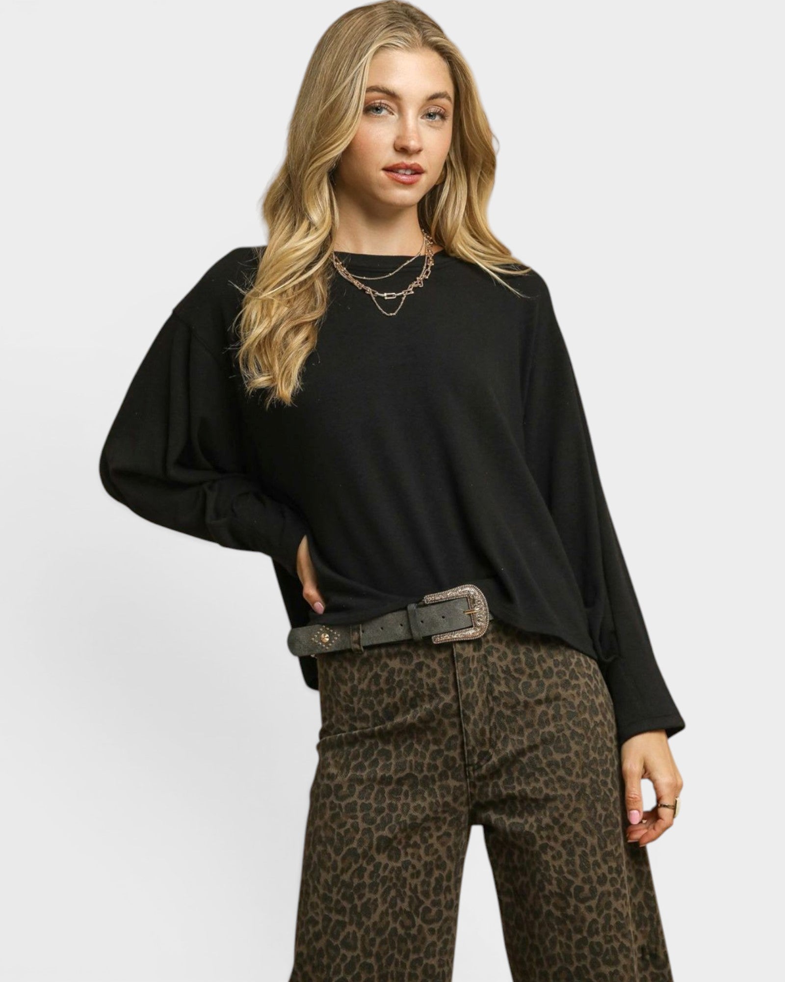 Woman wearing a black sweater and leopard print pants on a white background