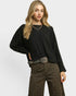 Woman wearing a black sweater and leopard print pants on a white background