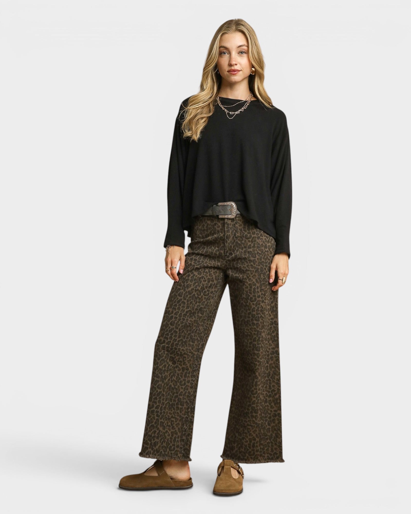 Woman wearing a black top and patterned brown pants on a white background