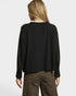 Person wearing a black long-sleeve top and leopard print pants on a white background