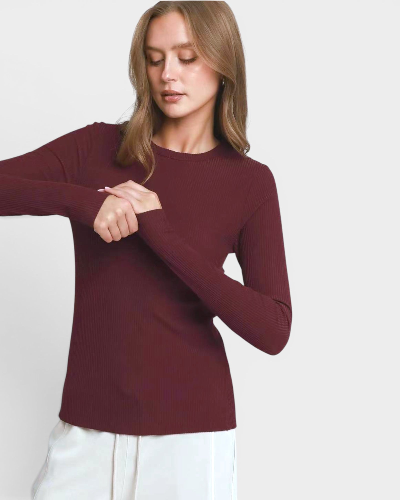 Woman wearing a burgundy long-sleeve top against a white background