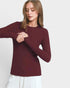 Woman wearing a burgundy long-sleeve top against a white background