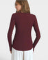 Person wearing a burgundy long-sleeve top on a white background