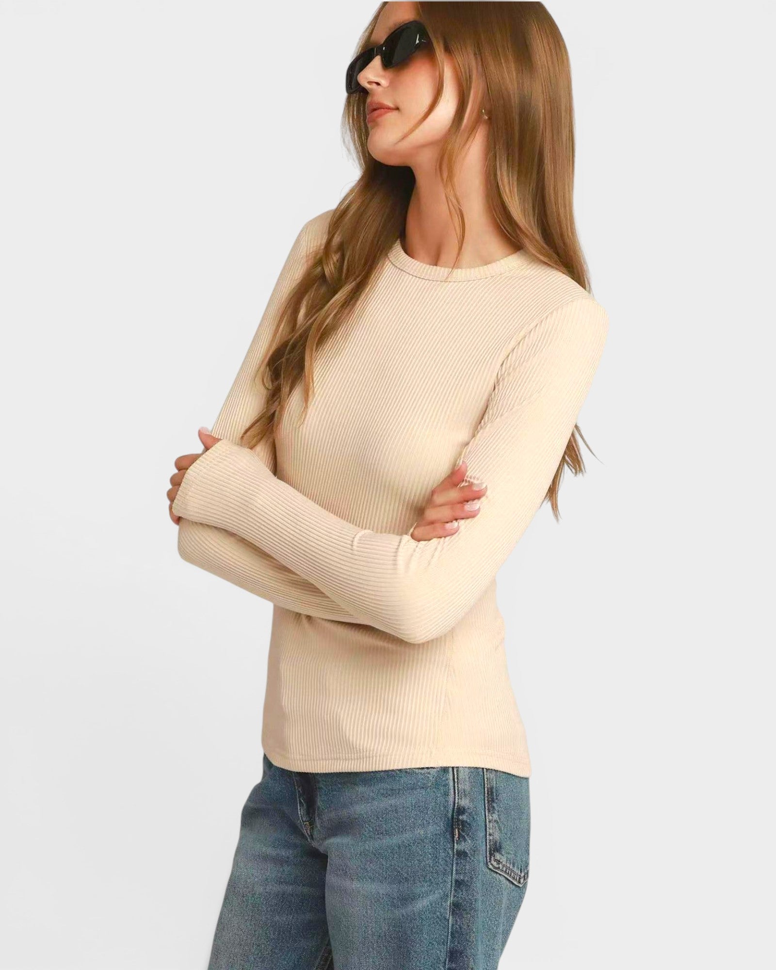 Woman wearing a beige sweater and blue jeans on a white background
