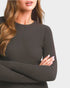 Woman wearing a dark ribbed sweater with a plain background