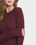 Maroon sweater worn by a person on a light gray background