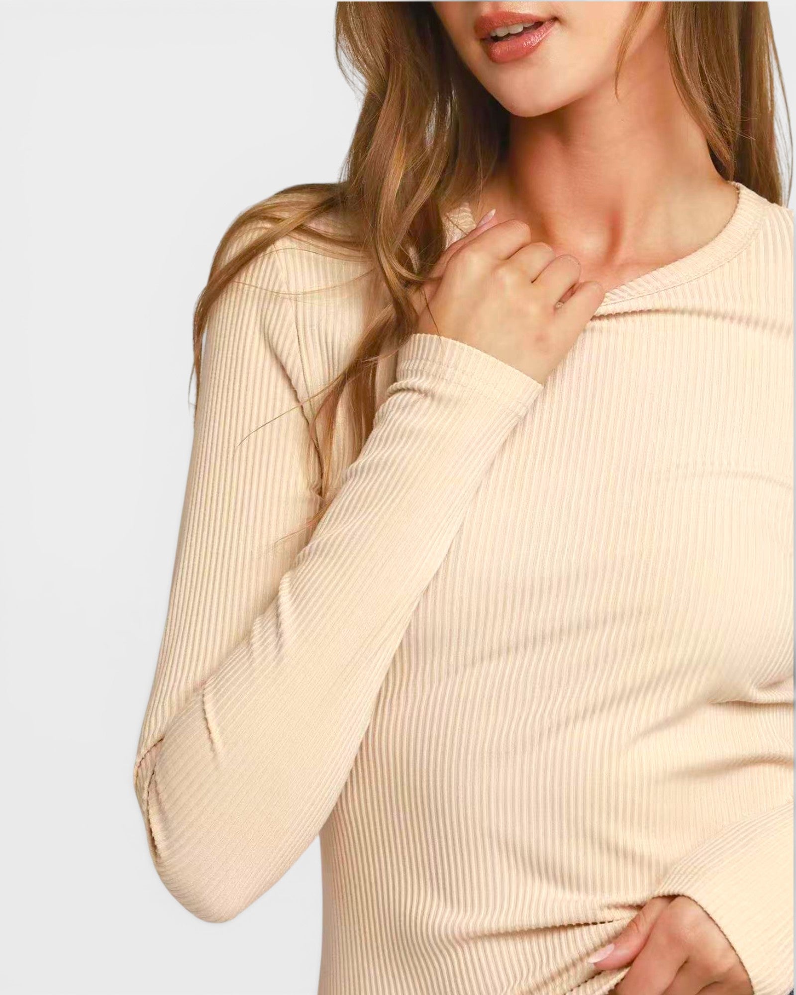 Woman wearing a beige ribbed sweater against a light background