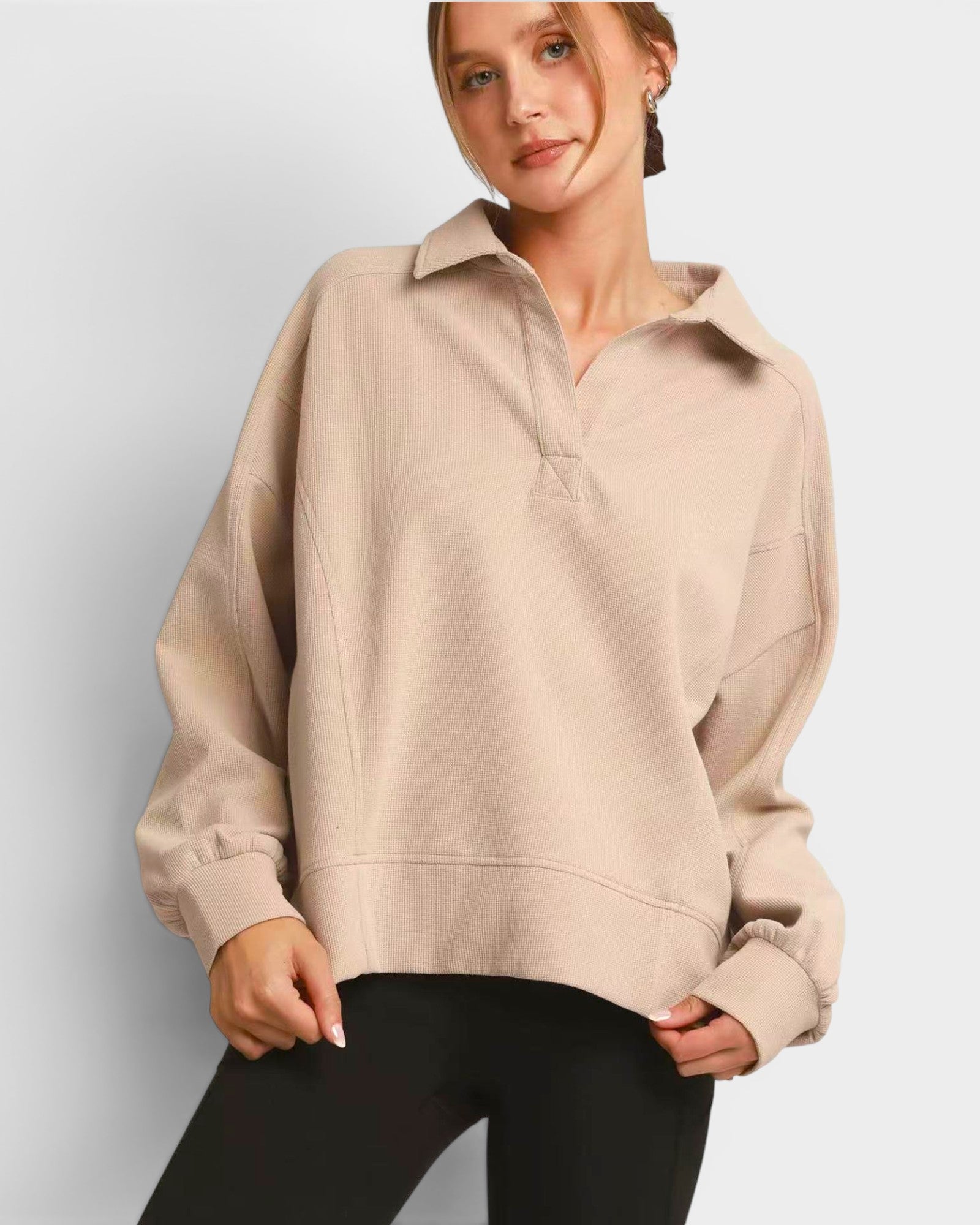 Woman wearing a beige pullover with a plain background