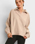 Woman wearing a beige pullover with a plain background