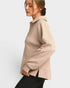 Woman wearing a beige pullover with a plain background