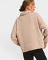 Woman wearing a beige pullover with a plain background