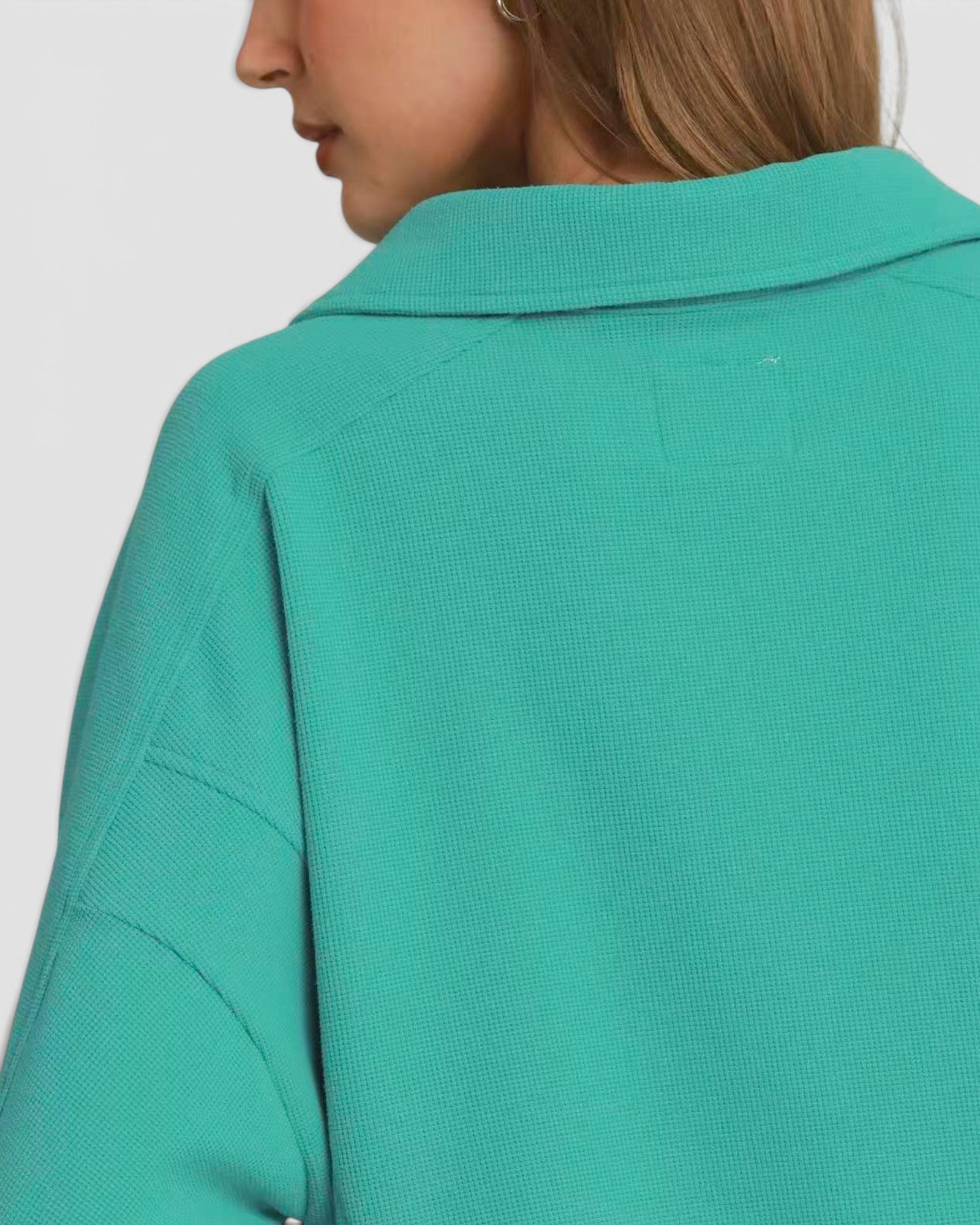 Green shirt worn by a person on a plain background