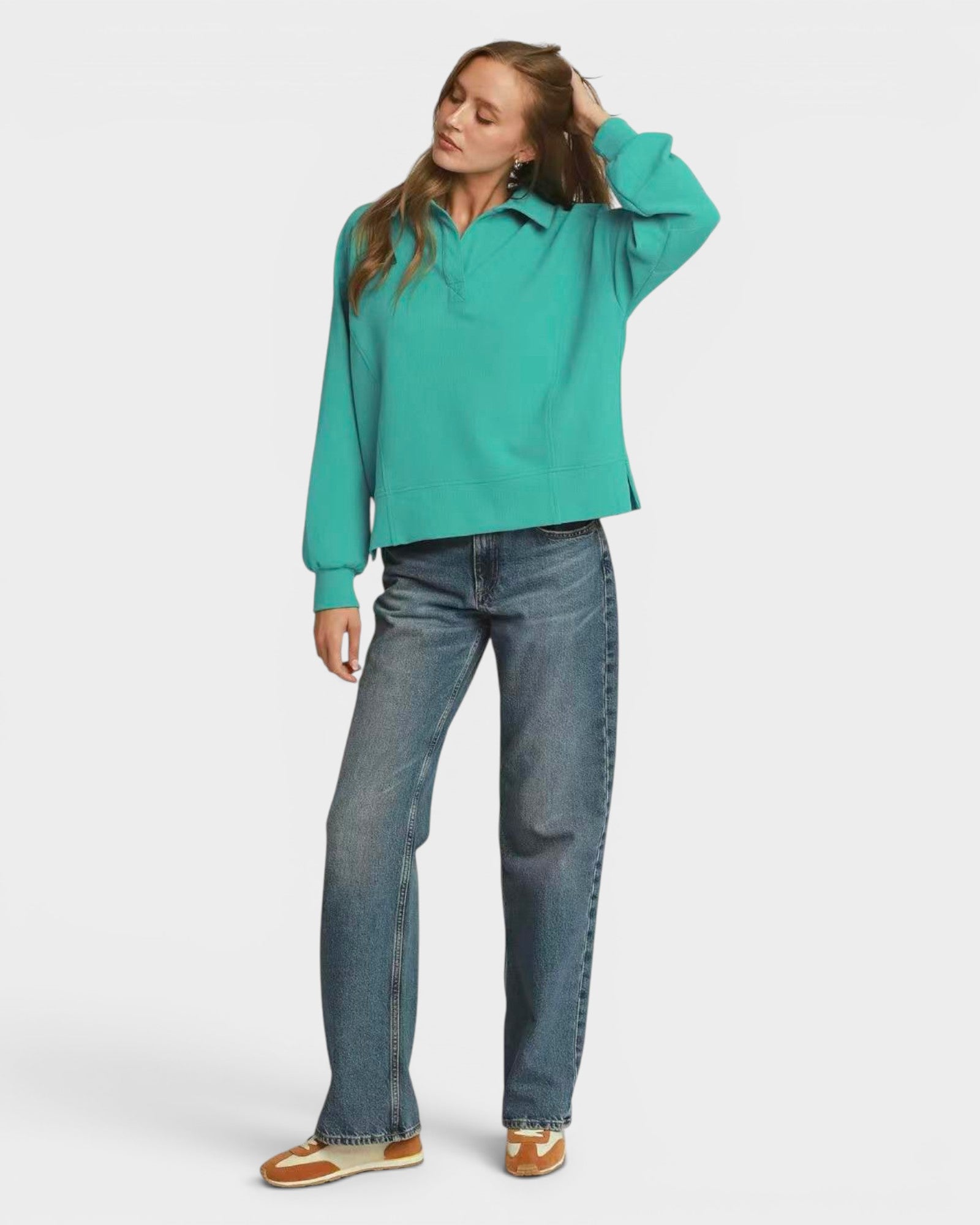 Person wearing a teal sweatshirt and blue jeans on a white background