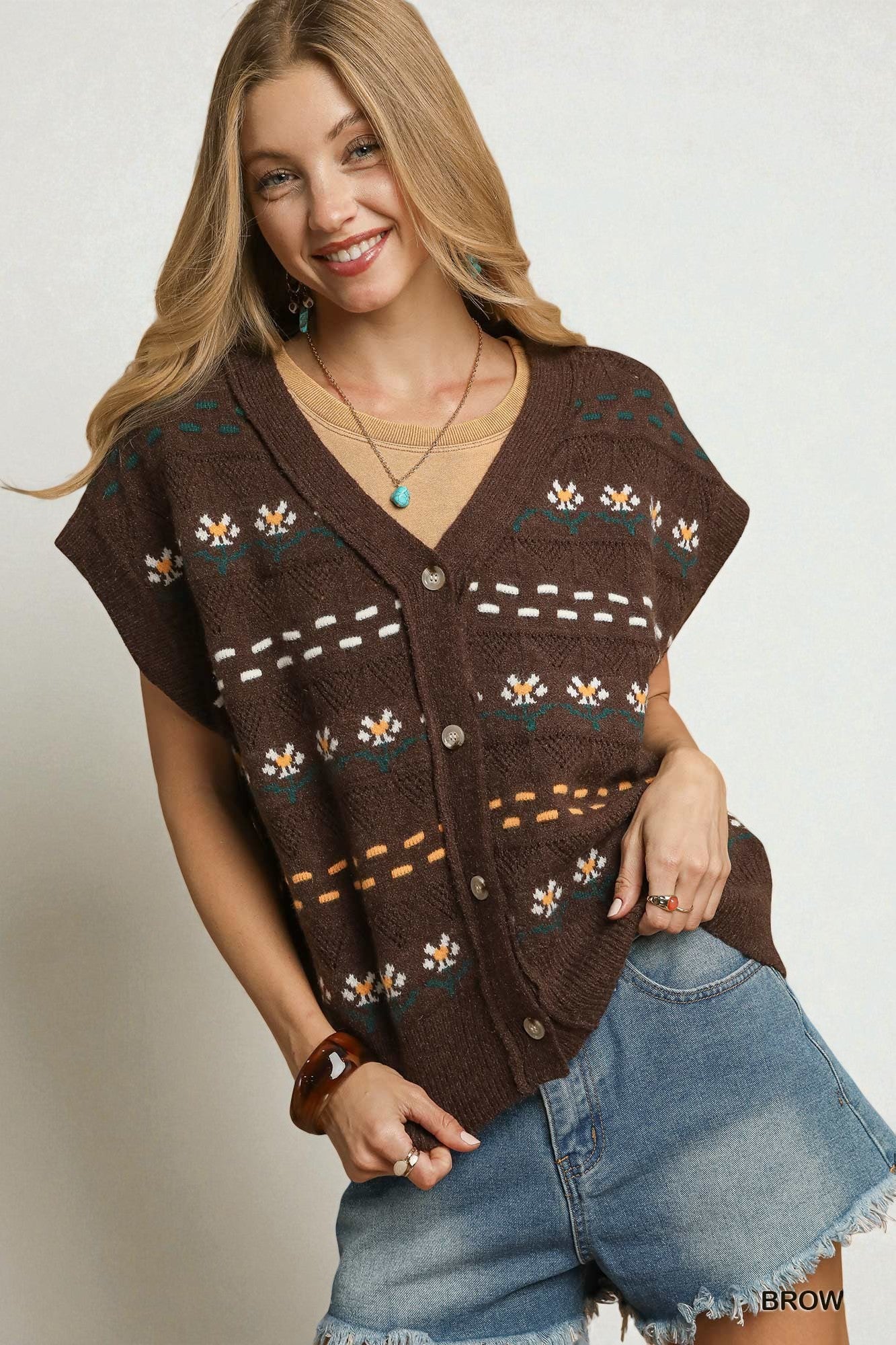 Woman wearing a brown patterned vest over a denim shirt on a plain background