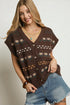 Woman wearing a brown patterned vest over a denim shirt on a plain background