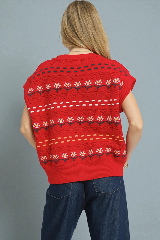 Person wearing a red patterned sleeveless sweater against a gray background