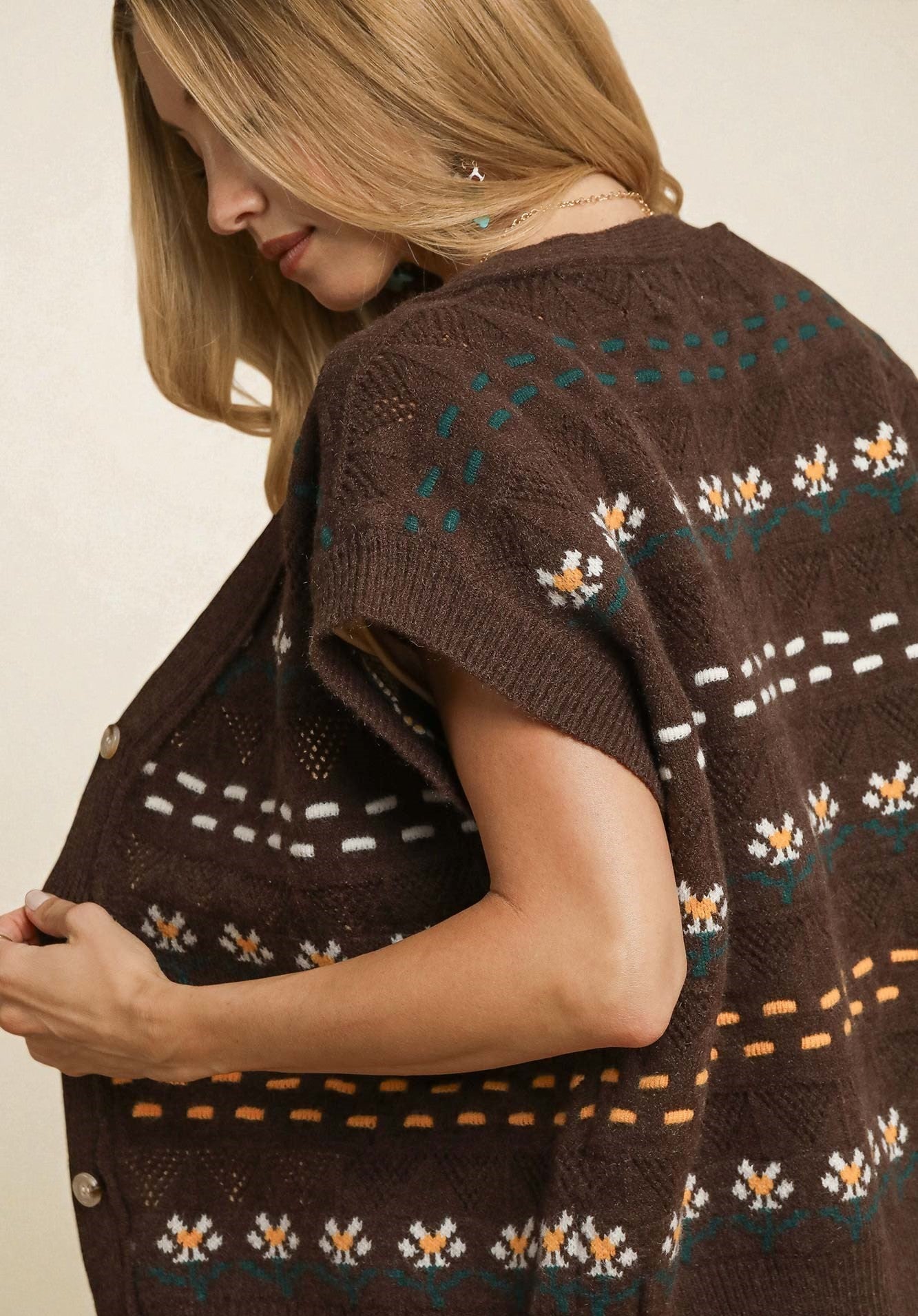 Woman wearing a brown patterned cardigan against a beige background