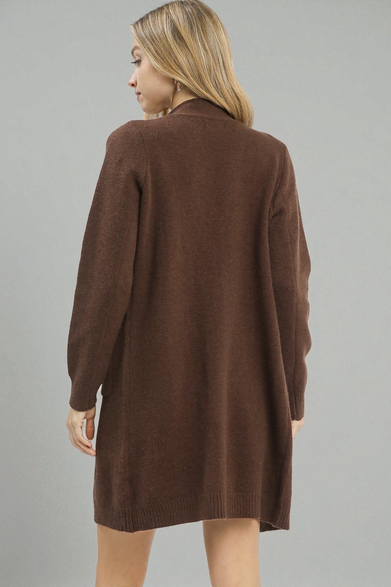 Woman wearing a brown cardigan against a gray background