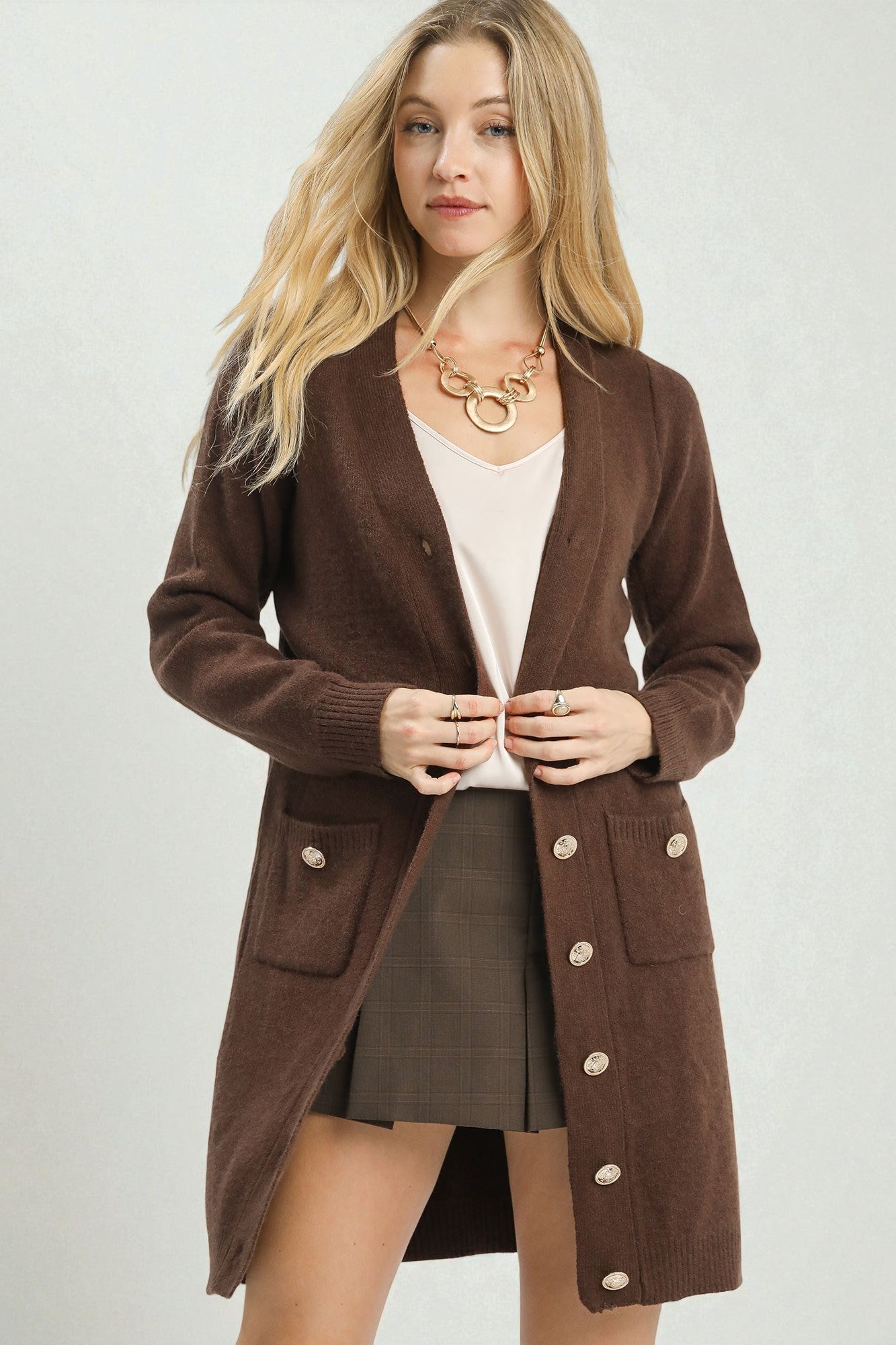 Woman wearing a brown cardigan with button details on a plain background