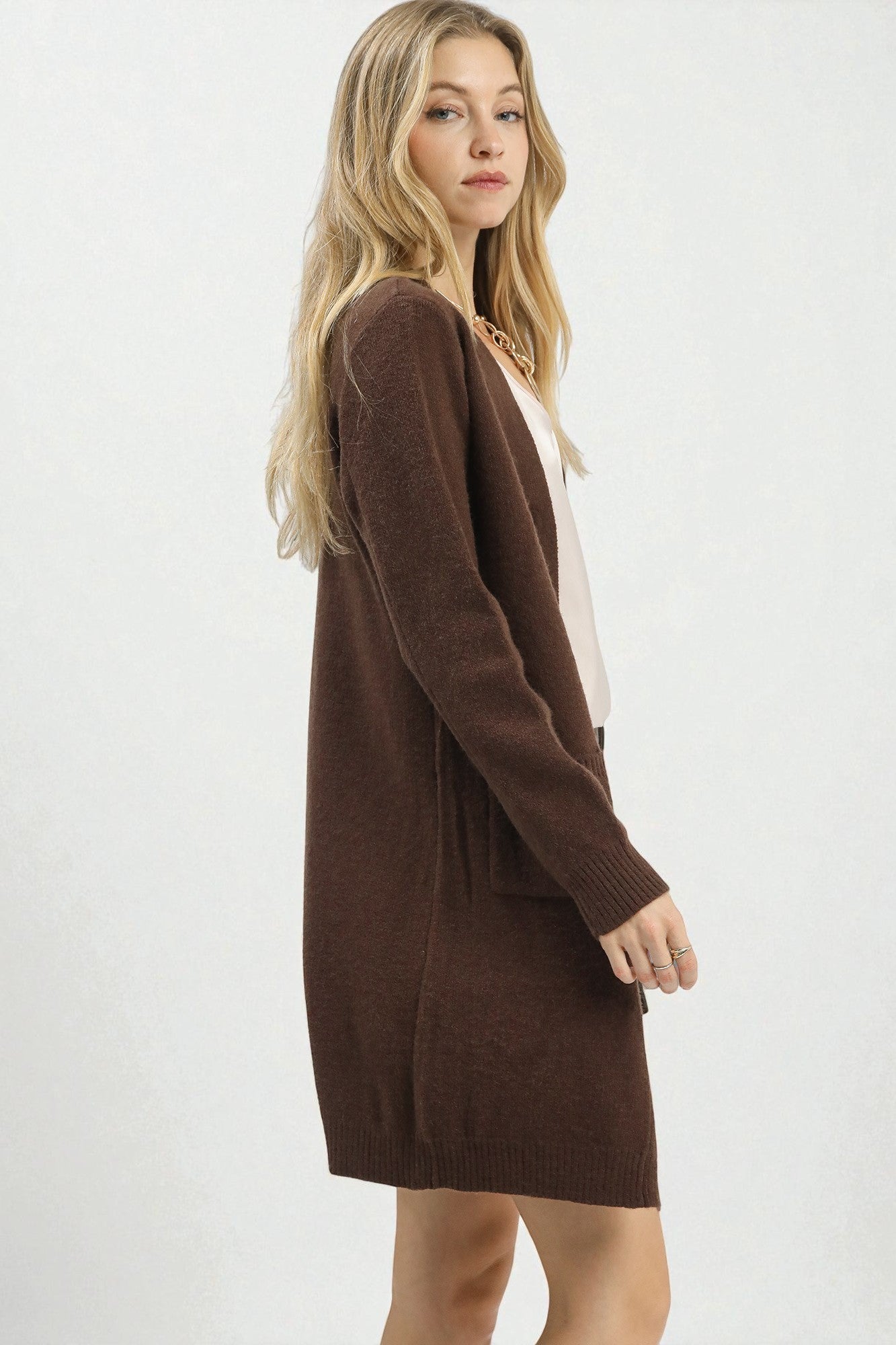 Woman wearing a brown cardigan over a white top on a white background