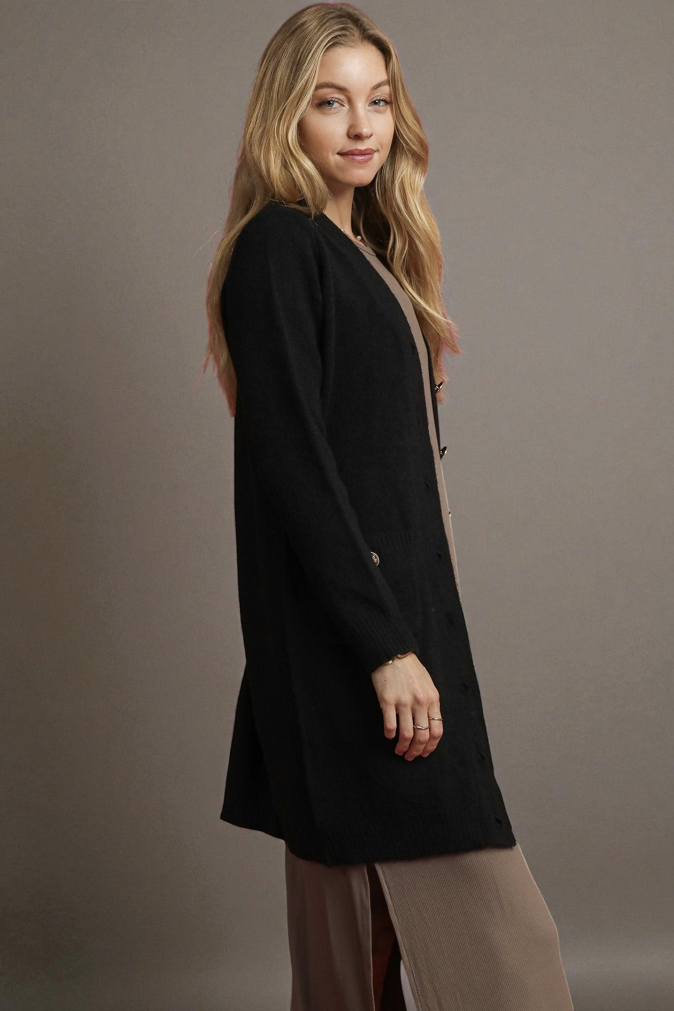 Woman wearing a black cardigan against a plain background