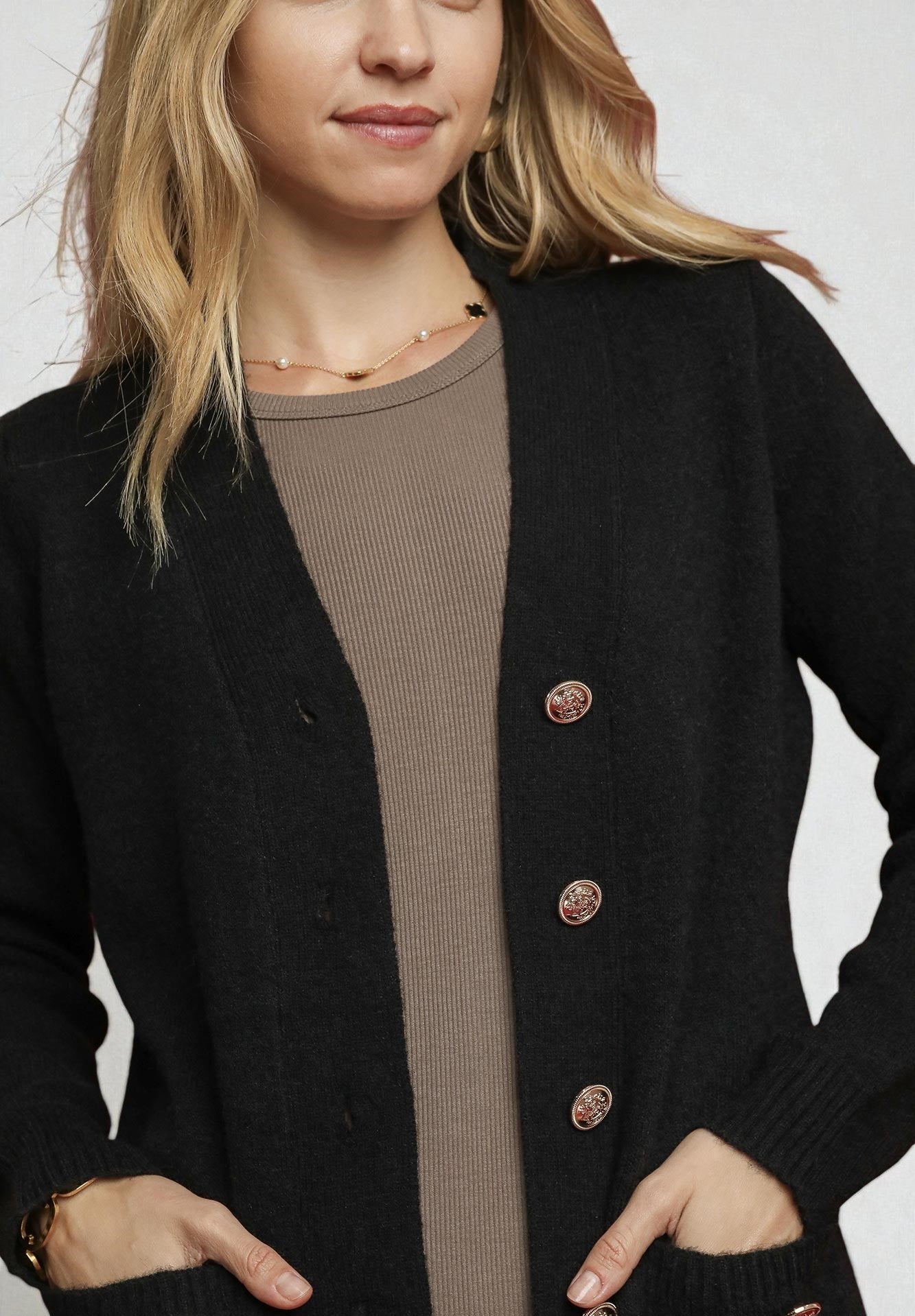 Person wearing a black cardigan with buttons on a white background