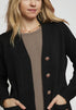 Person wearing a black cardigan with buttons on a white background