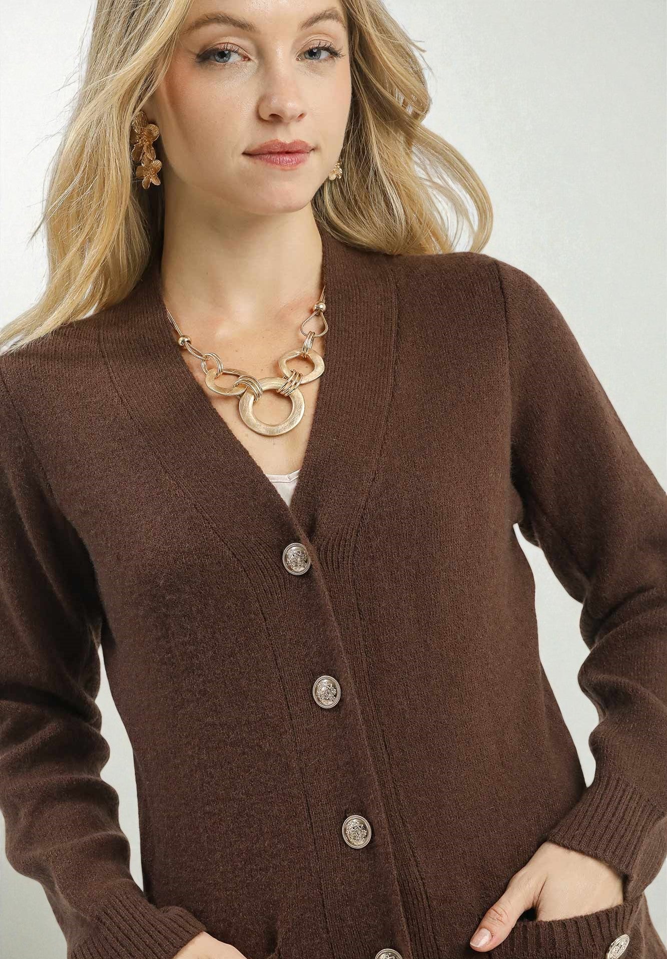 Woman wearing a brown cardigan with a plain background