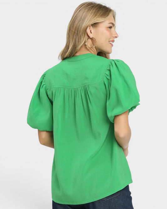 Woman wearing a green blouse with puff sleeves on a white background