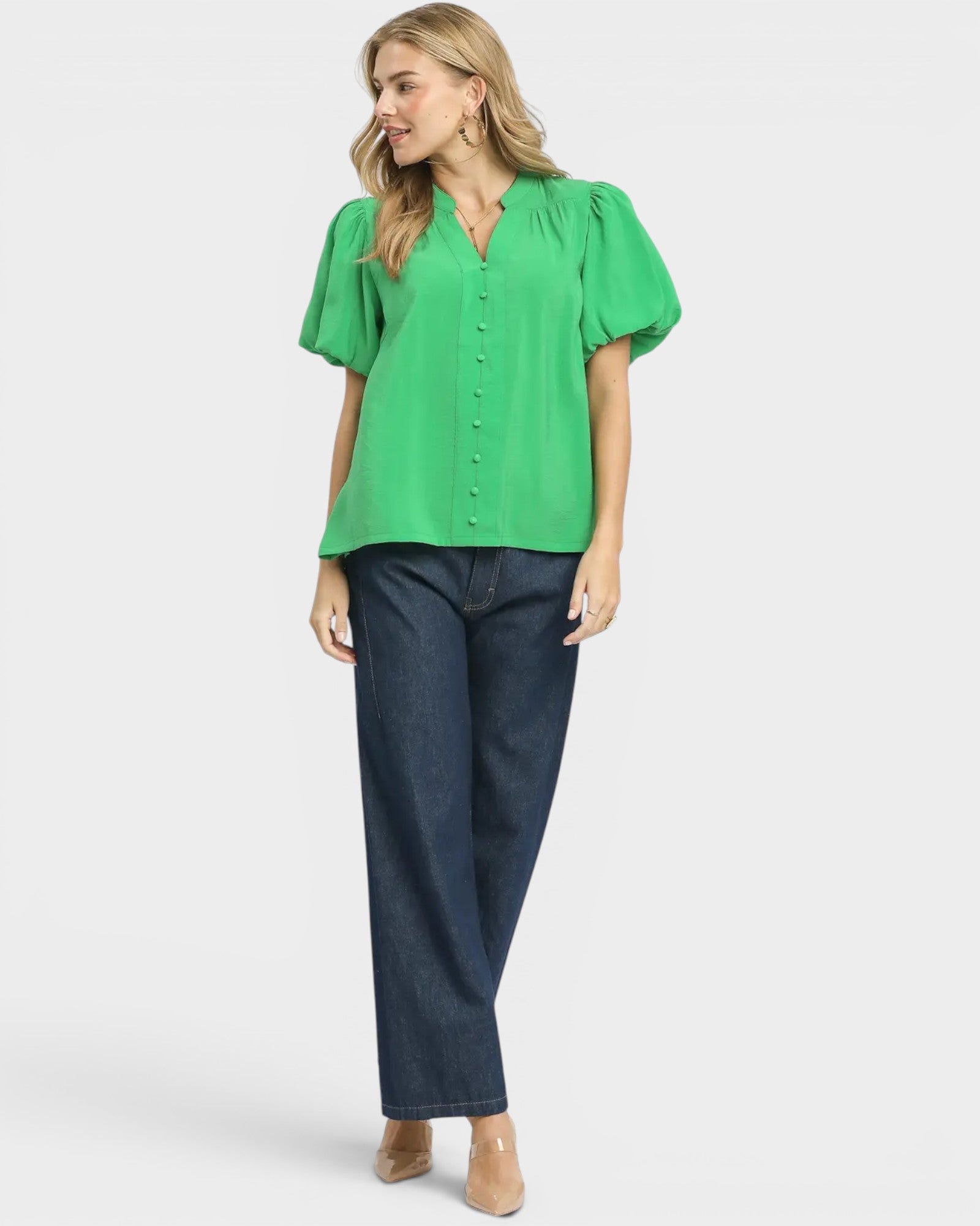 Woman wearing a green blouse and blue jeans on a white background