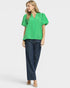 Woman wearing a green blouse and blue jeans on a white background