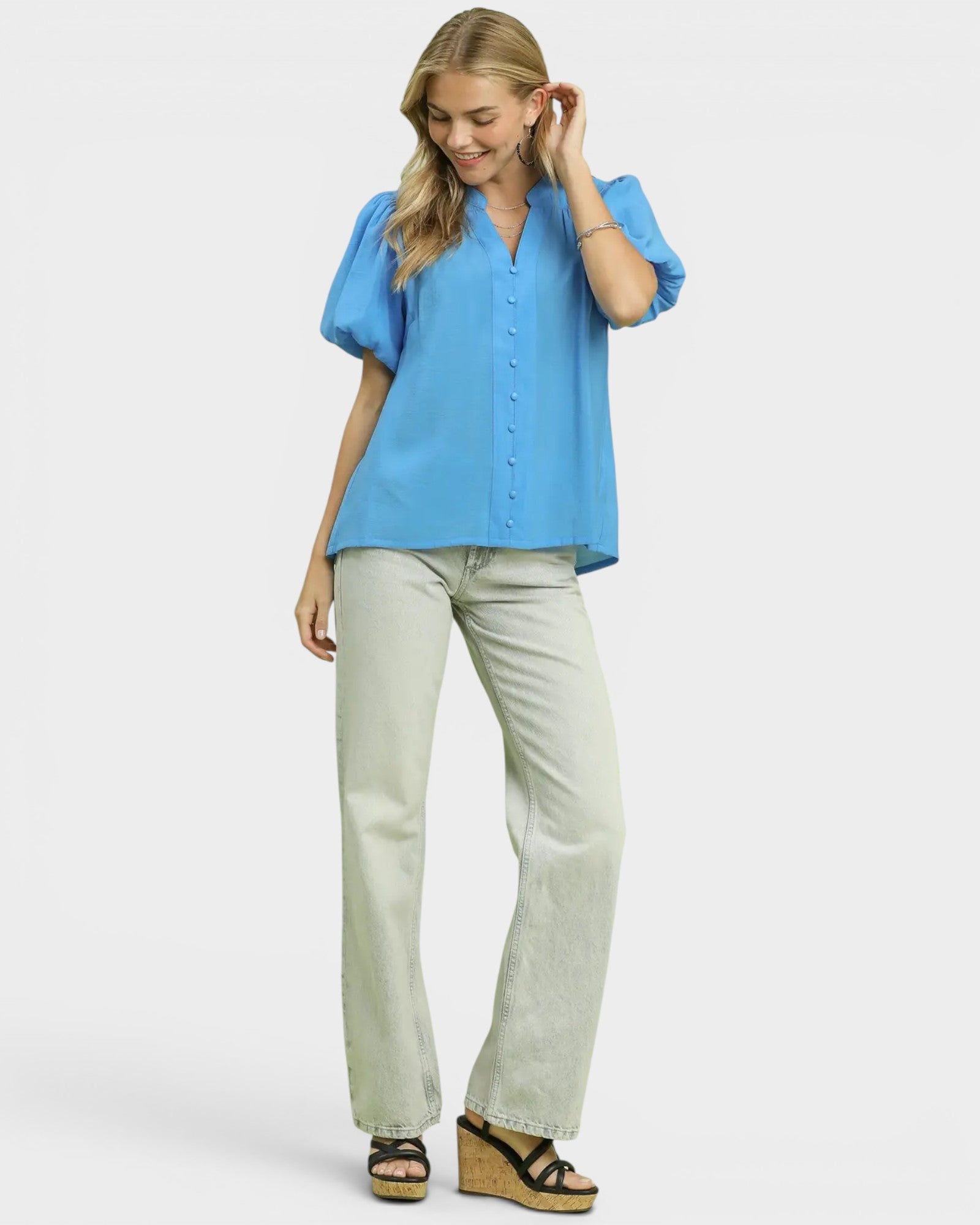 Woman wearing a blue blouse and light gray pants on a white background