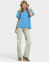 Woman wearing a blue blouse and light gray pants on a white background
